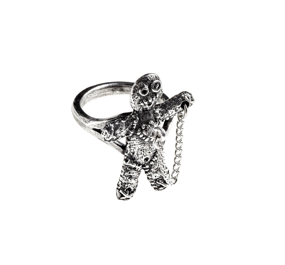 Close-up of voodoo doll ring showing detailed figure design, heart puncture point, and removable pin on safety chain.