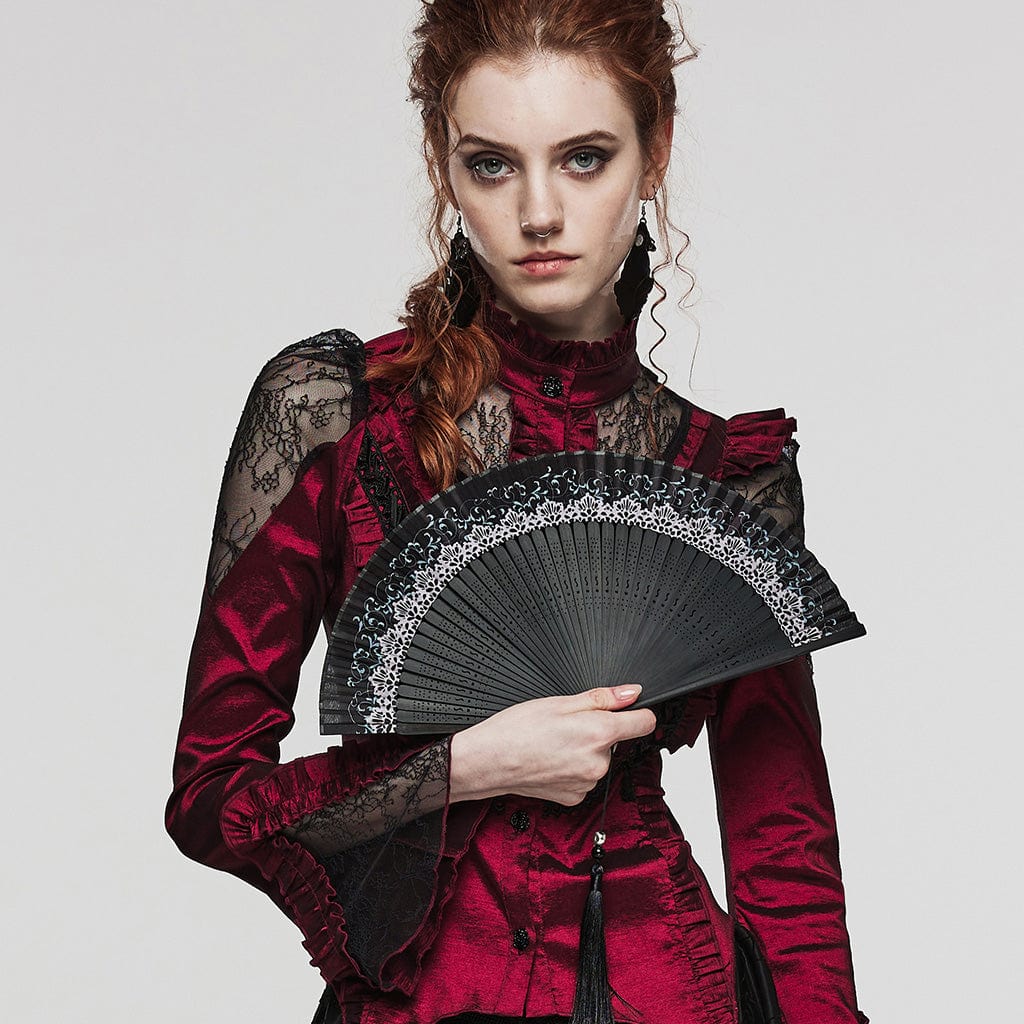 A close-up of the model holding the Enchanted folding hand fan, highlighting its black wooden frame, fabric leaves, and the skull bead detail attached to the tassel, blending elegance with gothic allure.