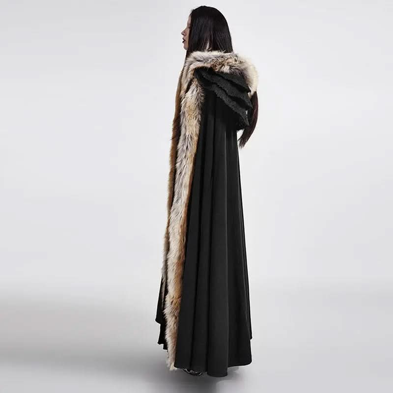 Side profile of model in a dark cloak coat with arm slits revealing movement, brown faux fur trim on the shoulders, and layered ruffles cascading down the back.

